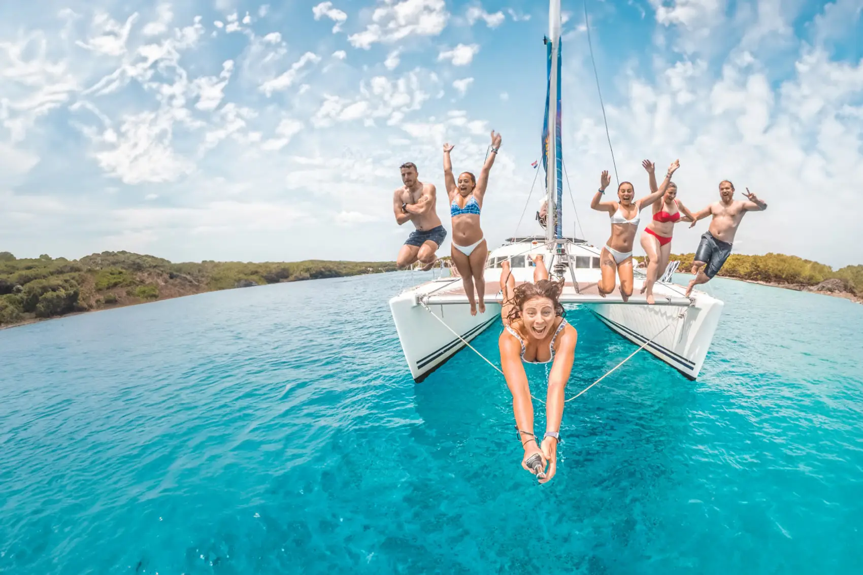 Group of people jump off a catamaran into the water in Croatia