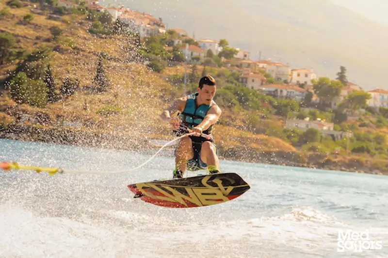 4 Reasons to Visit Poros Greece - Male on wakeboard in Poros Greece waterspouts jumping a wake. Photo by Ryan Brown of LostBoyMemoirs.com