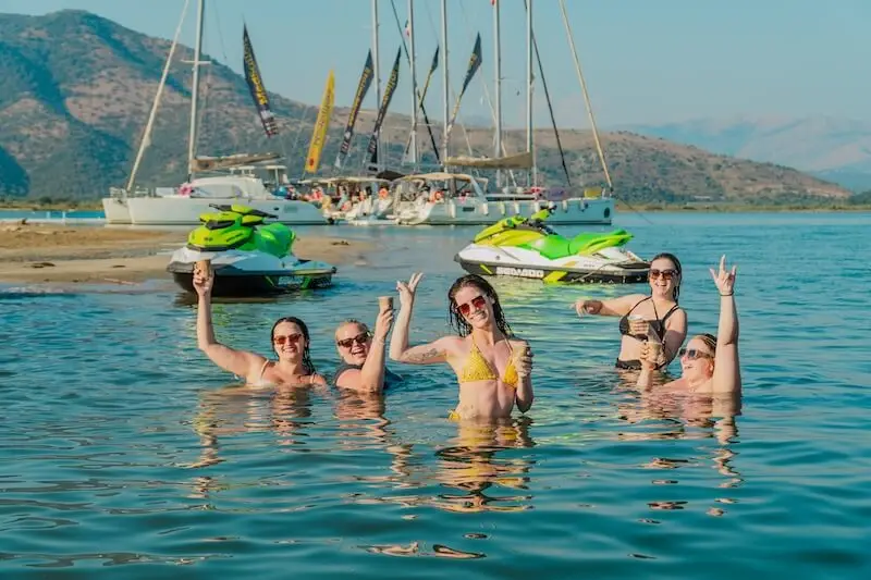 Group of woman swimming on a remote beach in Greece while island hopping in the summer with MedSailors for European music festivals.