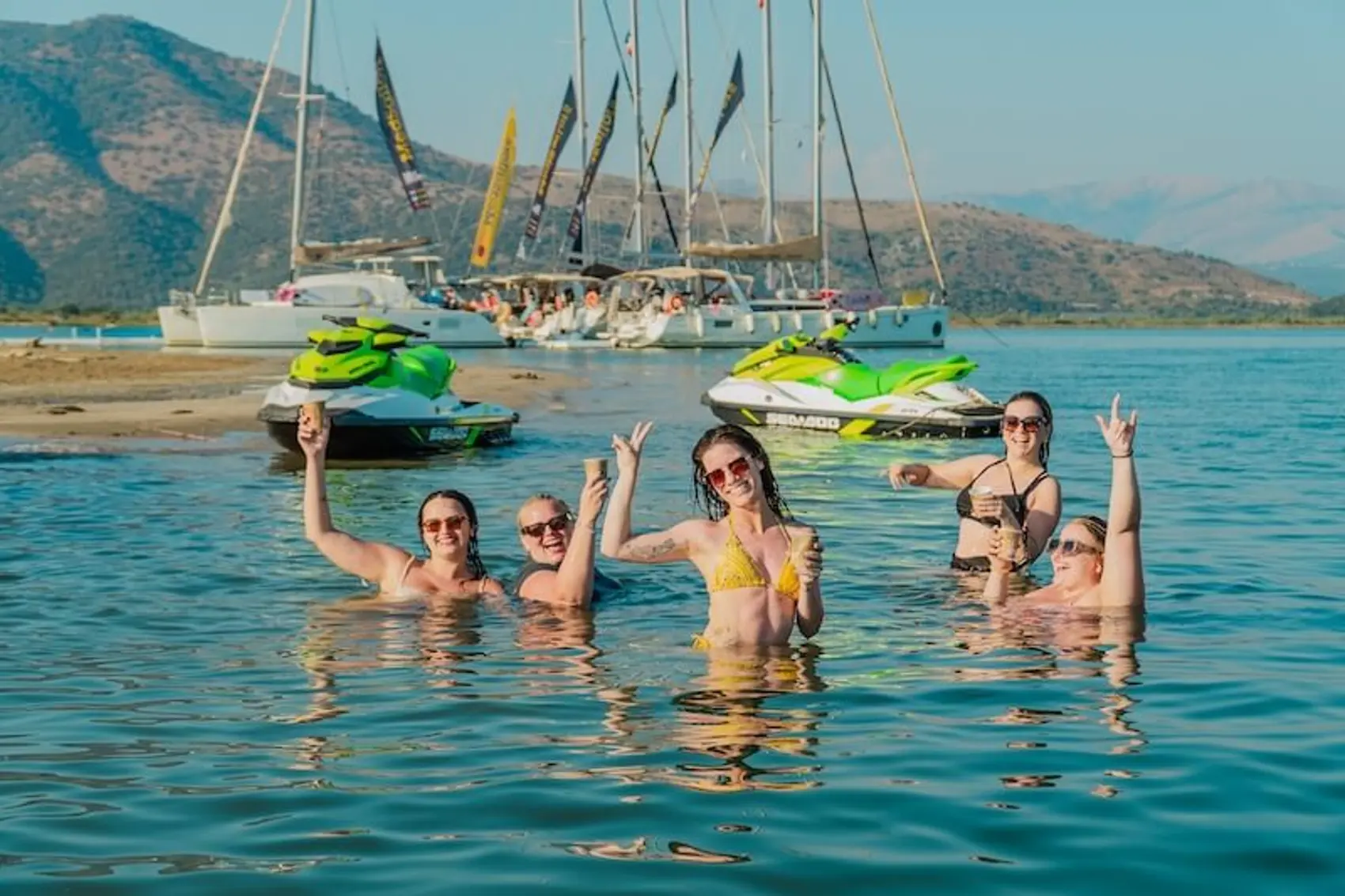 Group of woman swimming on a remote beach in Greece while island hopping in the summer with MedSailors for European music festivals.