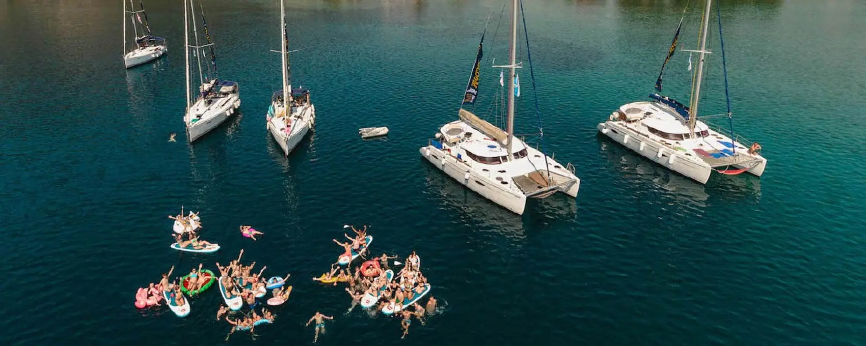 Epidavros bay and mountains with sailing yachts and people swimming. 