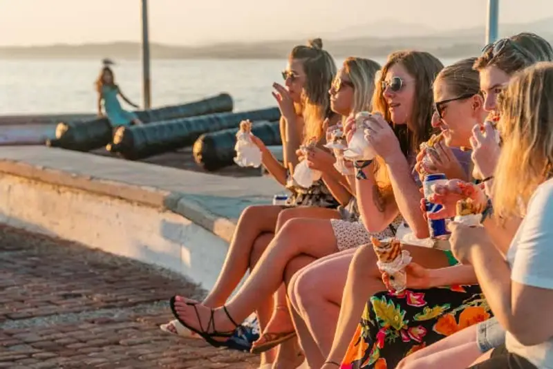 Young women eat gyros on waterfront in Greece