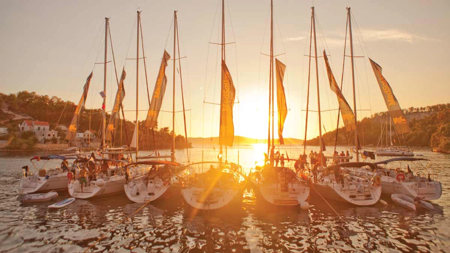 A photo of a flotilla of MedSailors yachts at sunset anchored in a bay on a sail week in the Mediterranean. 