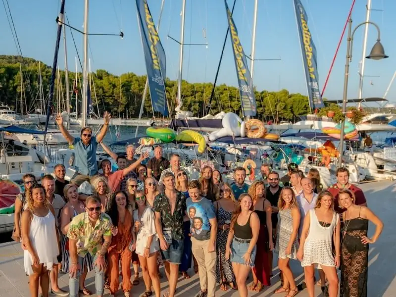 Large group of travellers standing together at a marina in Croatia before a group sailing and island hopping trip.