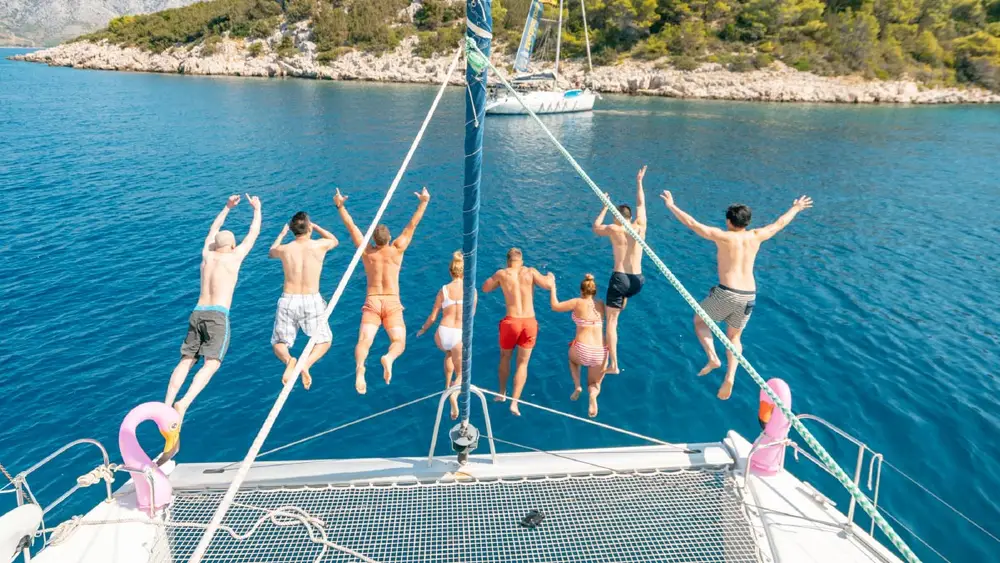 Group of people jump off a catamaran into the water in Croatia