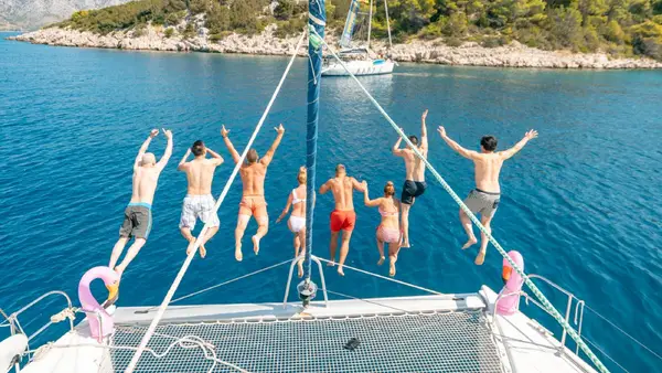 Group of people jump off a catamaran into the water in Croatia