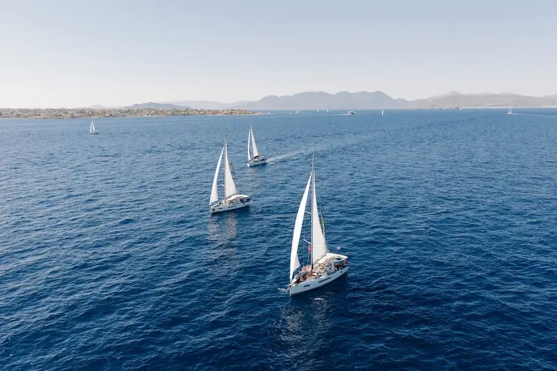 A fleet of MedSailors yachts sailing along the Greek coastline during a 2026 island hopping holiday for young travellers.