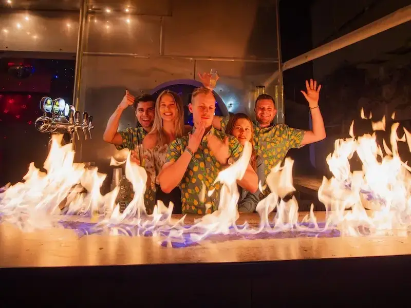Young Aussie and Kiwi backpackers party in a bar in Ermioni Greece with the bartop on fire as they dance 