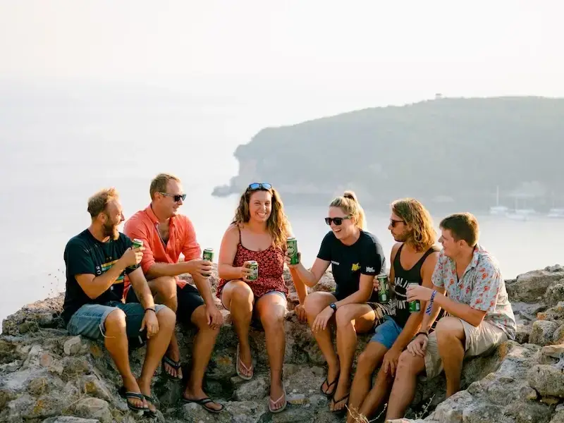 A group of backpackers sip drinks atop ruins of Parga fortress in Greece, one of the best party destinations in Europe.