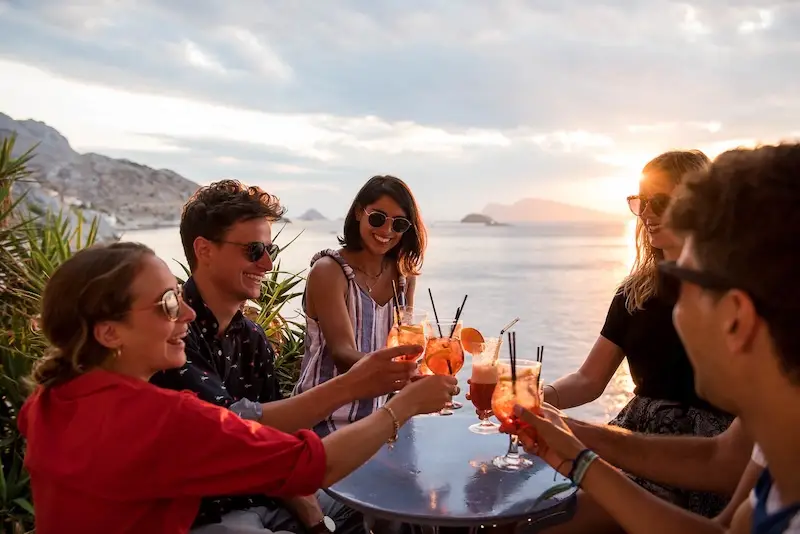 A group of young travellers having cocktails at sunset in Greece on an island hopping tour.