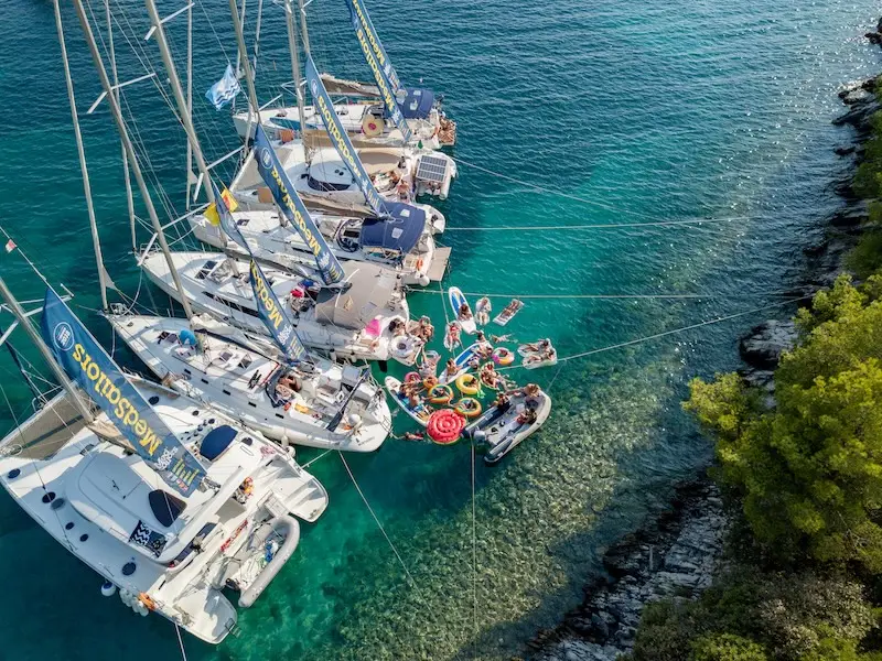 A group Aussies and Kiwis on a Europe sailing adventure celebrate on the back of a sailing yacht.