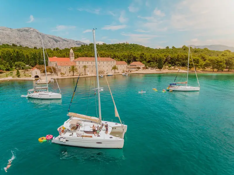 A catamaran filled with uni students anchored in a beautiful blue bay in Croatia with MedSailors.