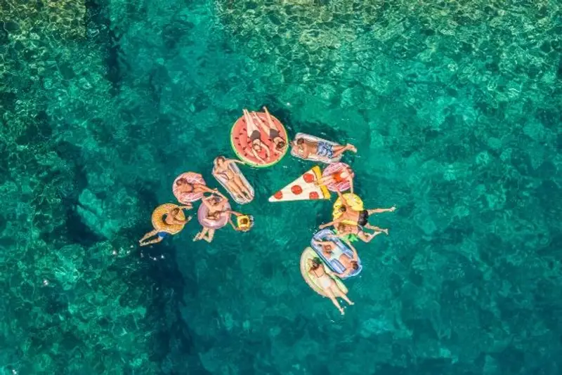 A group of young Gen Z and Millennial travellers floating in a breathtaking blue bay on an island hopping tour of Croatia. 