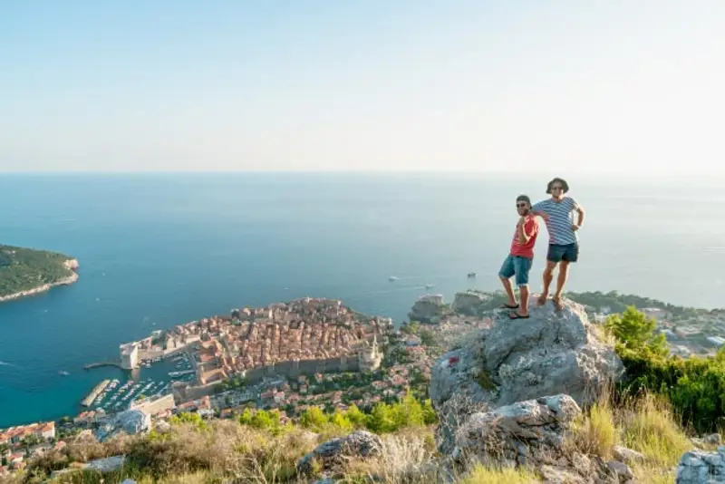 Two people hike above Dubrovnik Old Town in Croatia