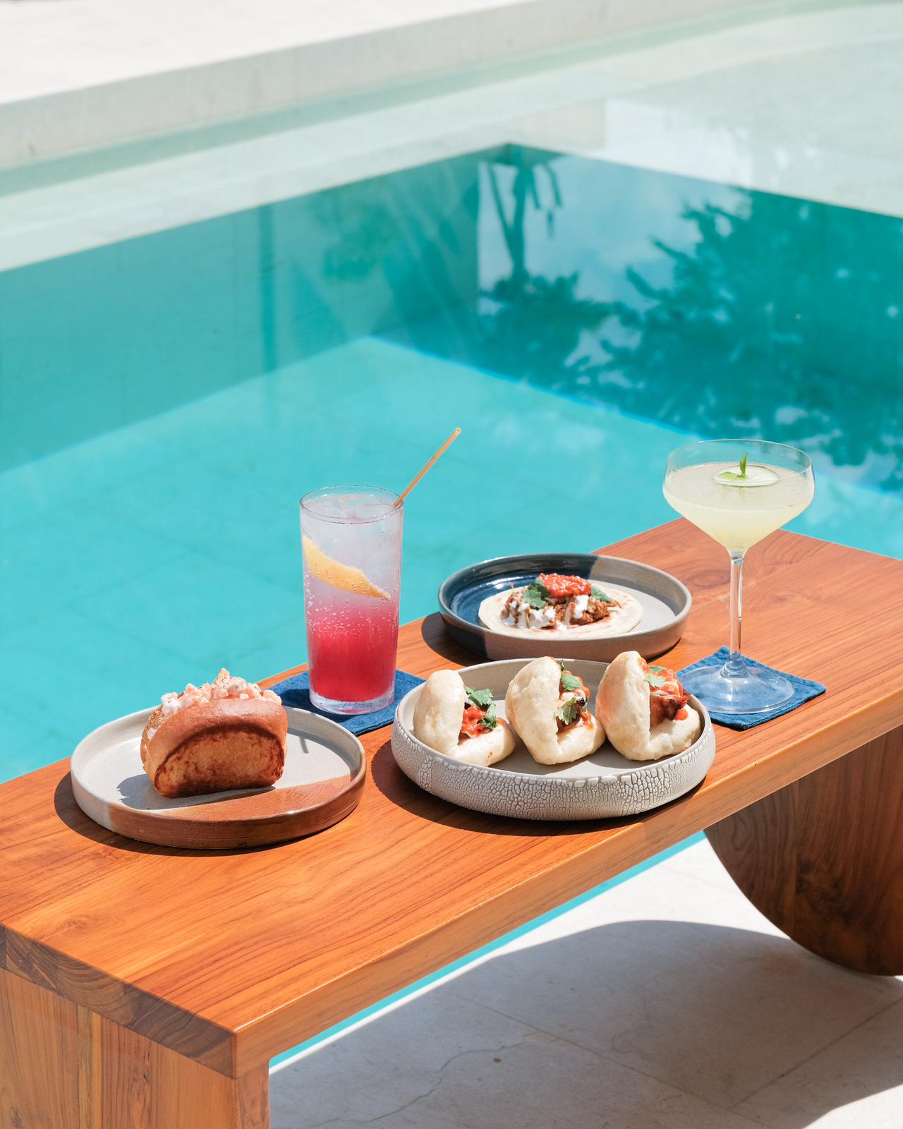 Cocktails and small plates on a table beside the Boni Beach pool.