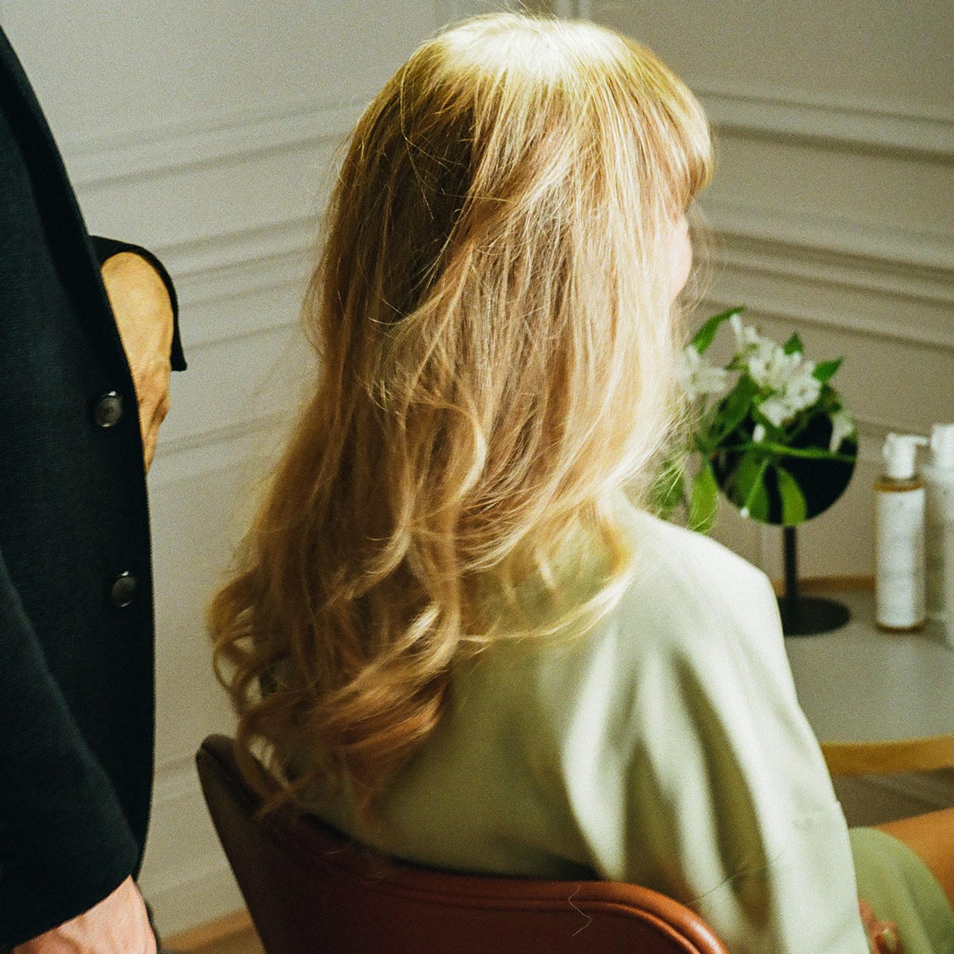 Photo of the back of Harklinikken Female Ambassador Lina Rafn's head with lightly curled blonde hair
