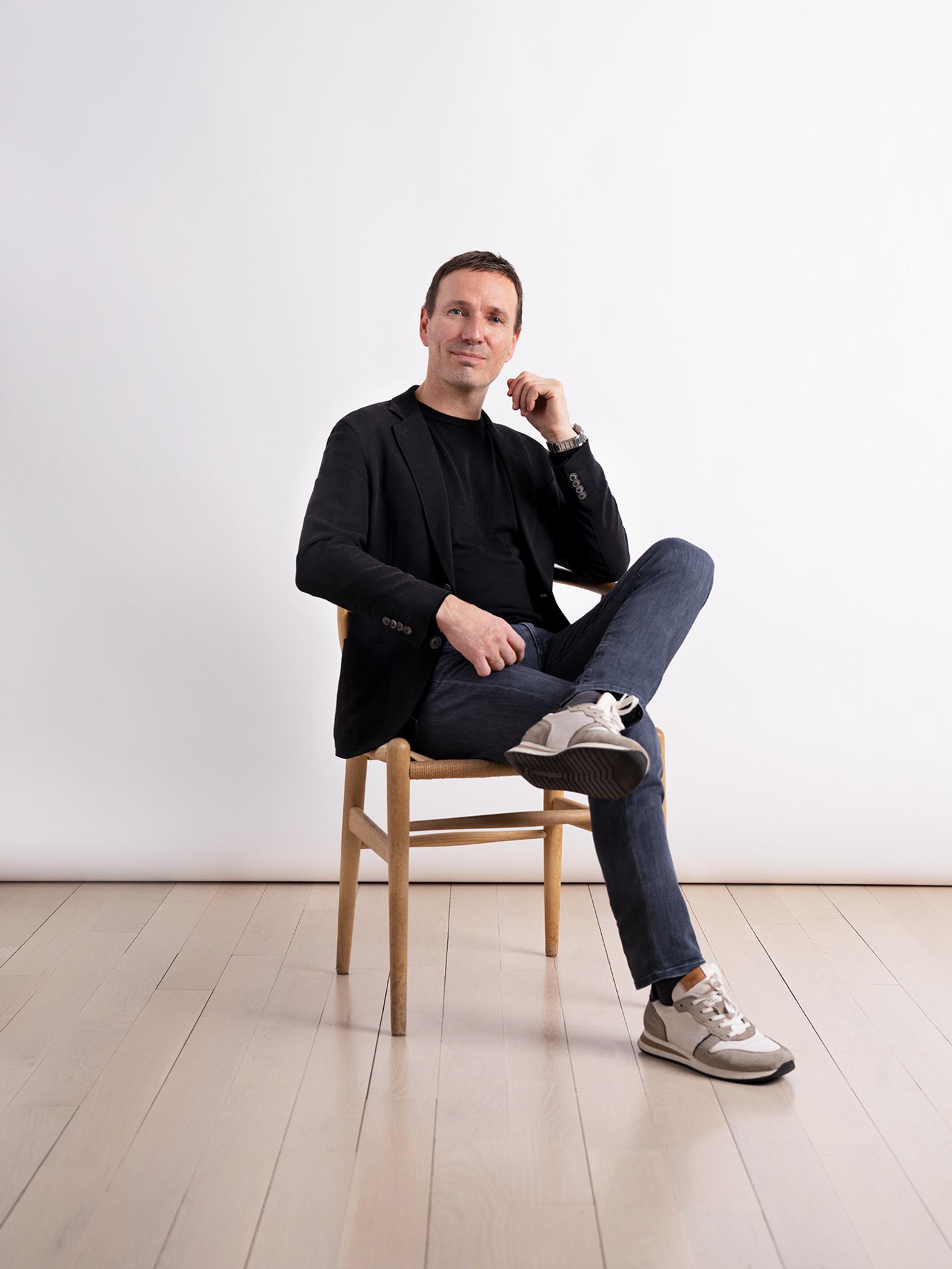 Harklinikken founder Lars Skojoth in chair, legs crossed, portrait image