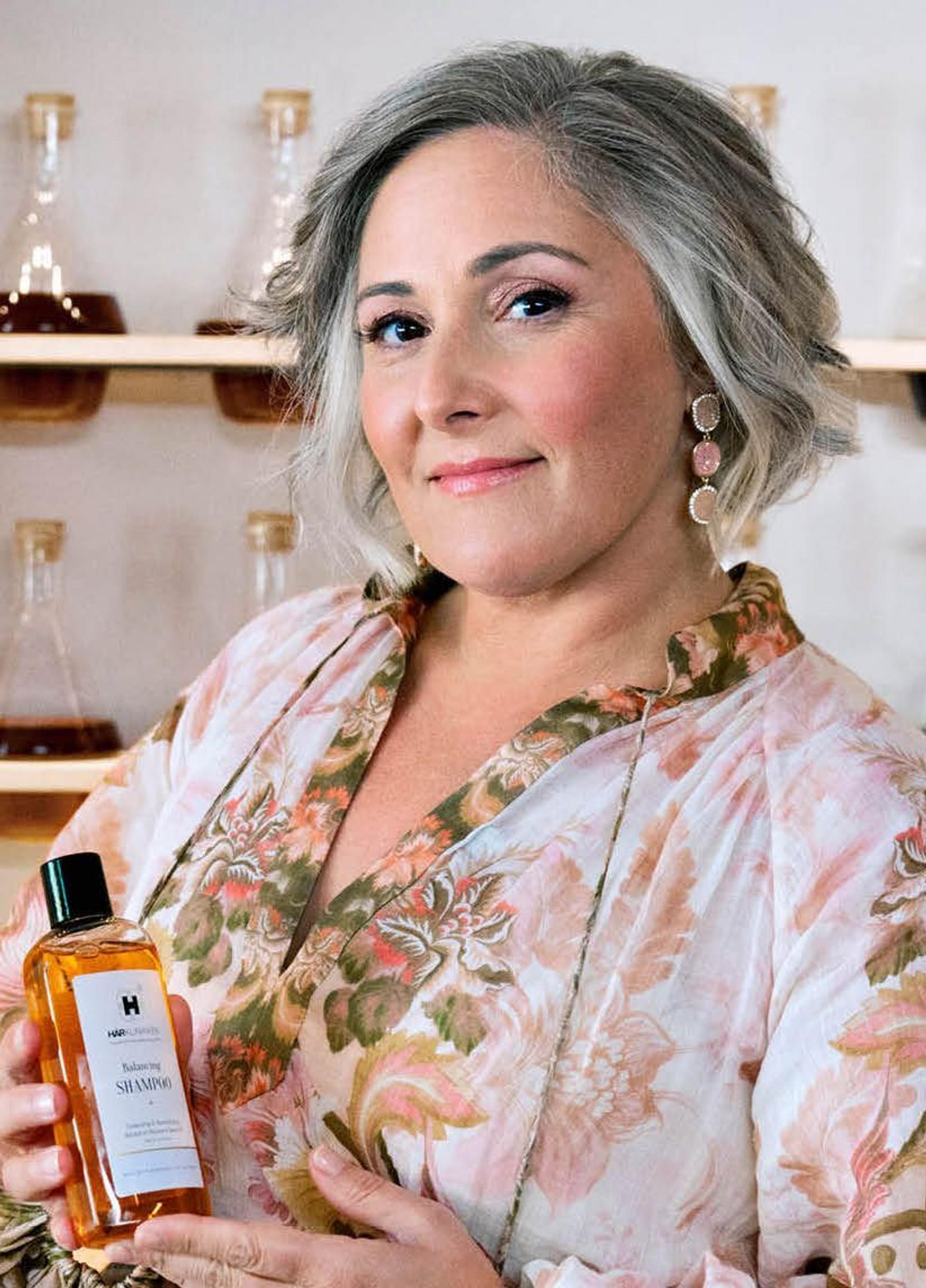 Side profile picture of Ricki Lake Holding Bottle of Harklinikken Balancing Shampoo