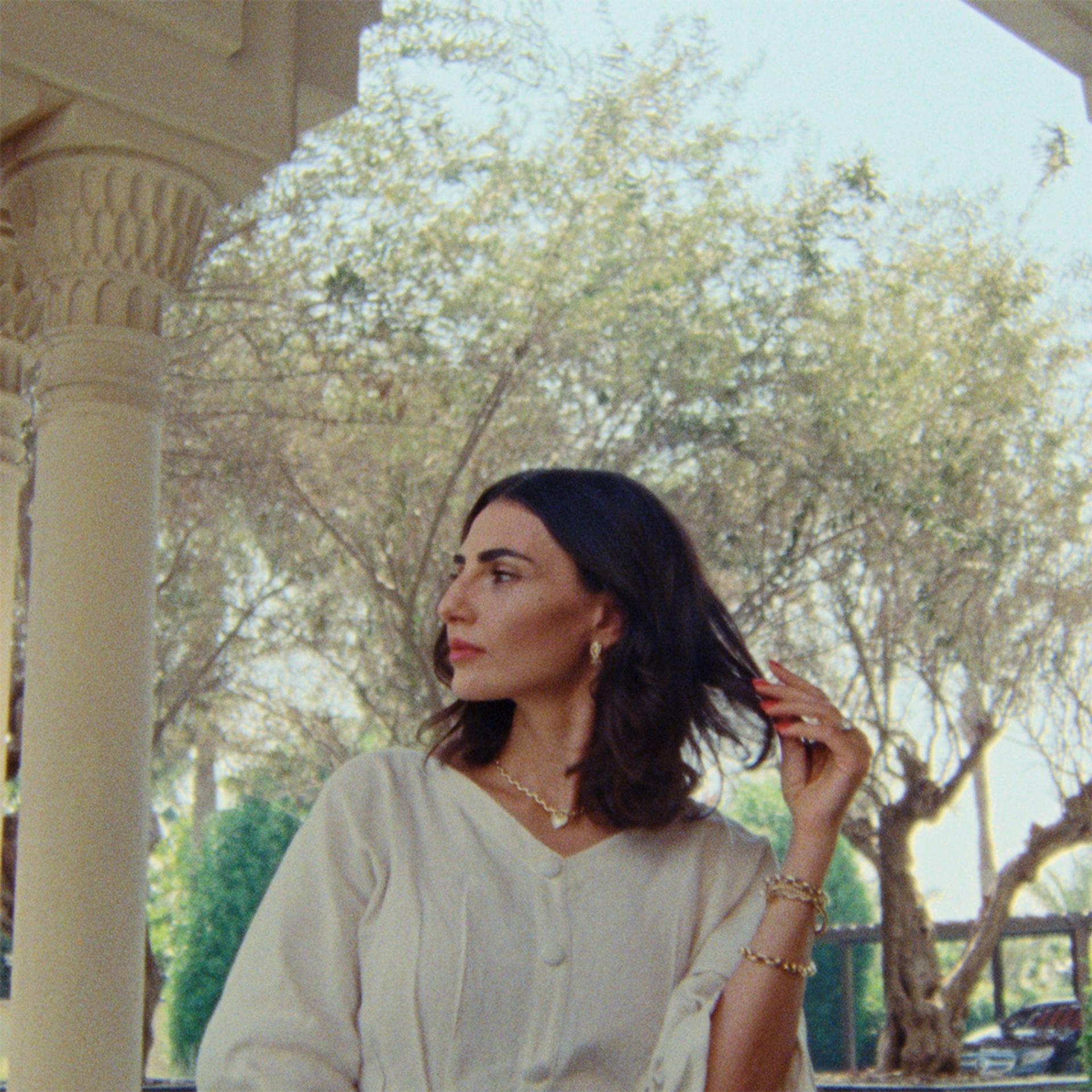 Sideway view of a woman with short dark hair wearing a white blouse looking away from the camera