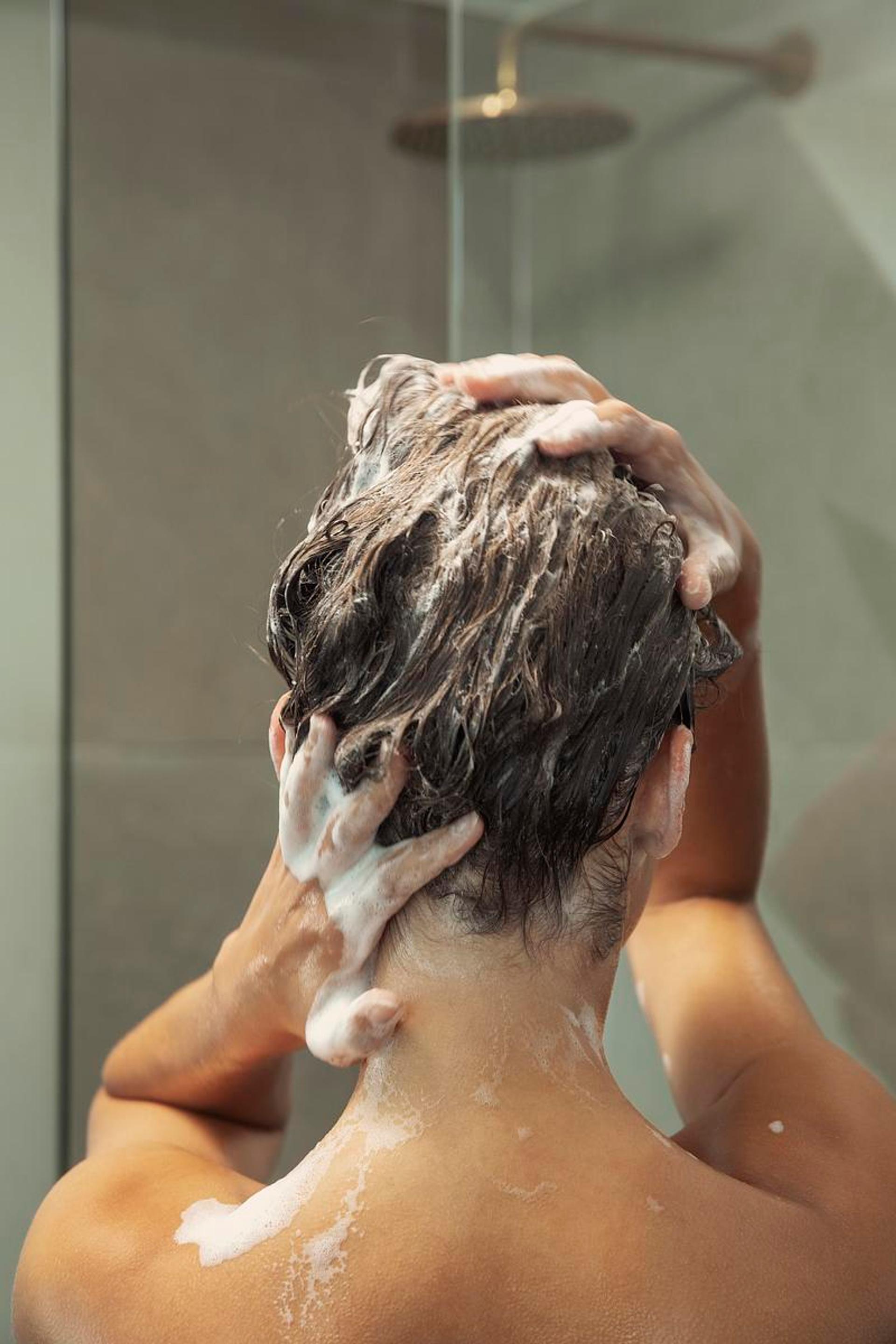 Photo of the back of head of a woman washing hair with Harklinikken Balancing Shampoo