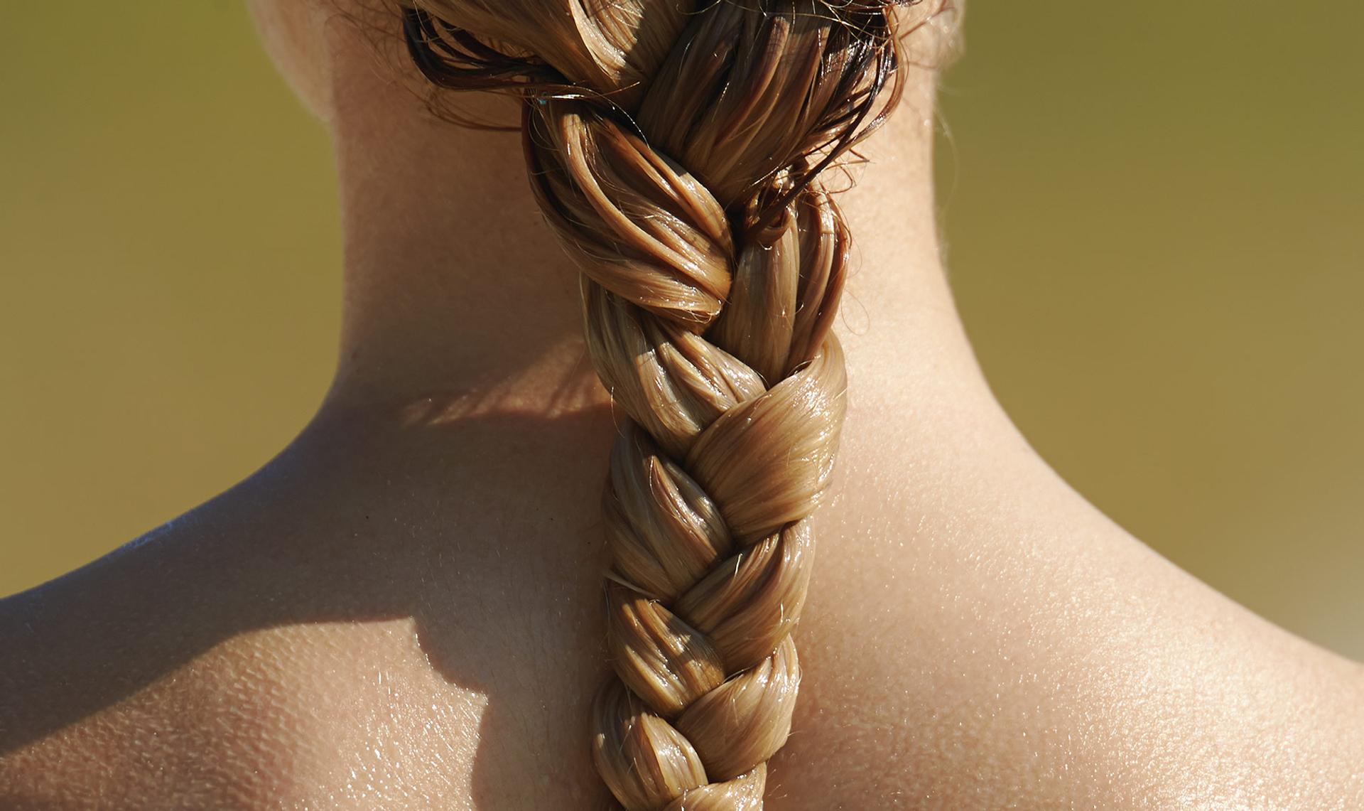 Image of the back of a women's neck and shoulders with wet braided hair down sitting down the length of the women's neck