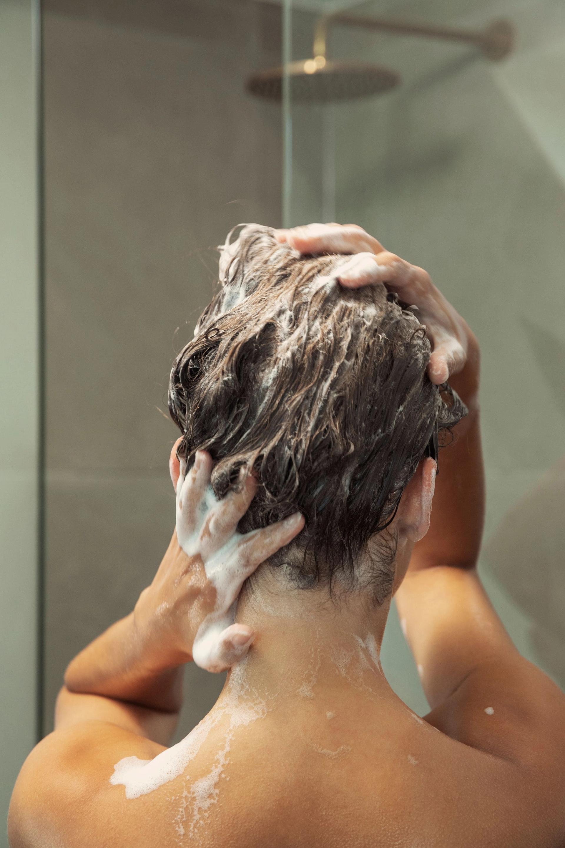 Back of Woman's head washing with shampoo in shower