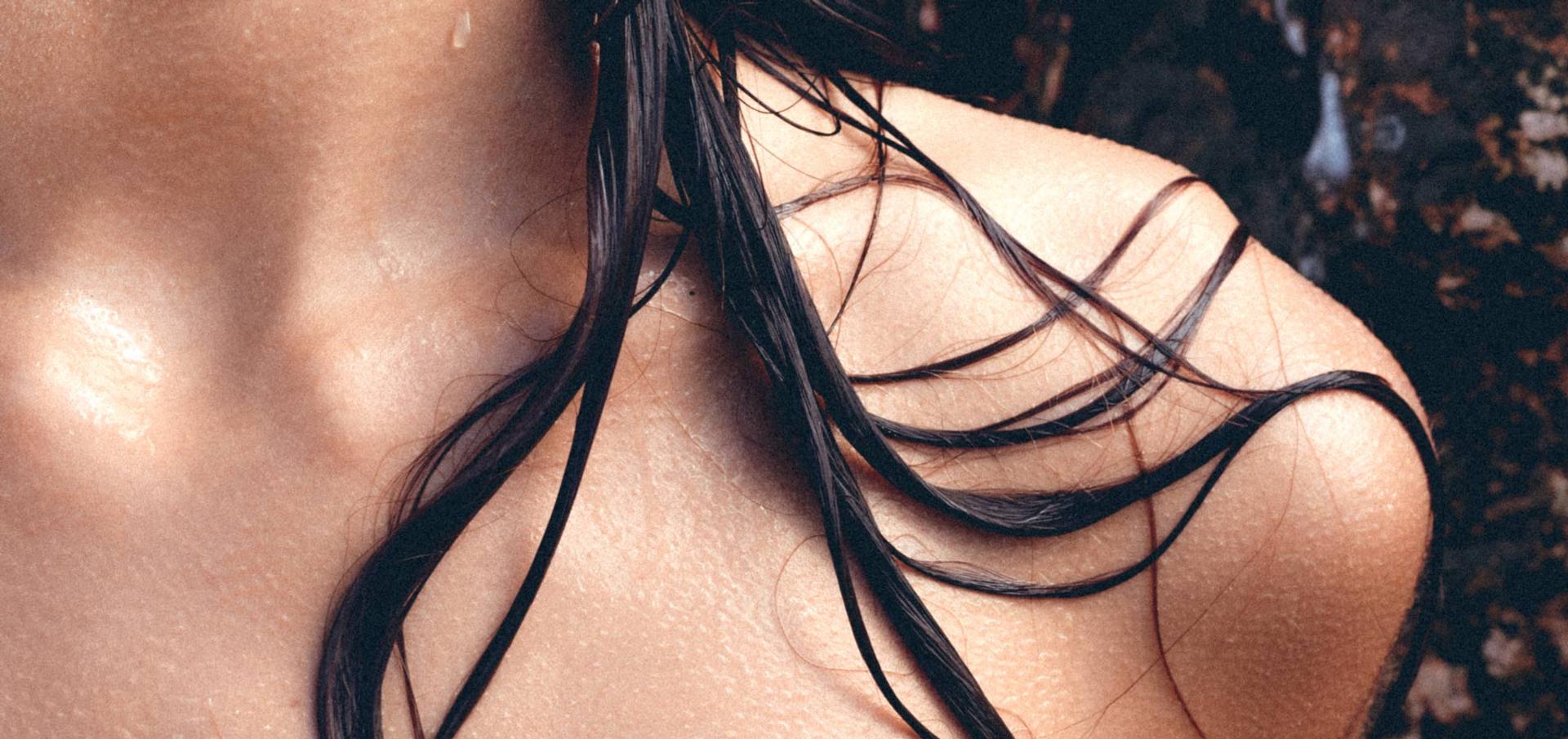 Partial neck and shoulder close up of a woman with wet hair strands on her shoulder