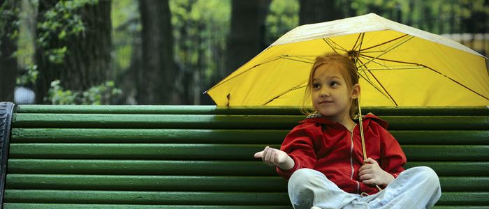Girl sitting on bench with umbrella