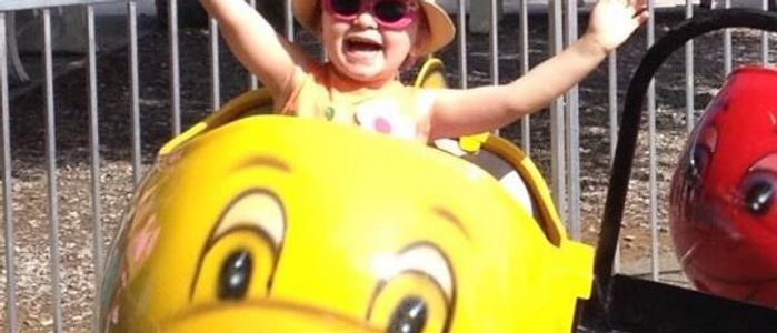 Little girl with sunglasses riding the Whales Kiddie Ride at DelGrosso's Amusement Park