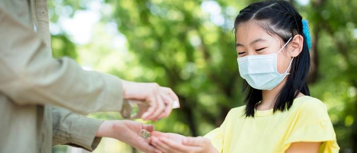 Small girl getting hand sanitizer from an adult