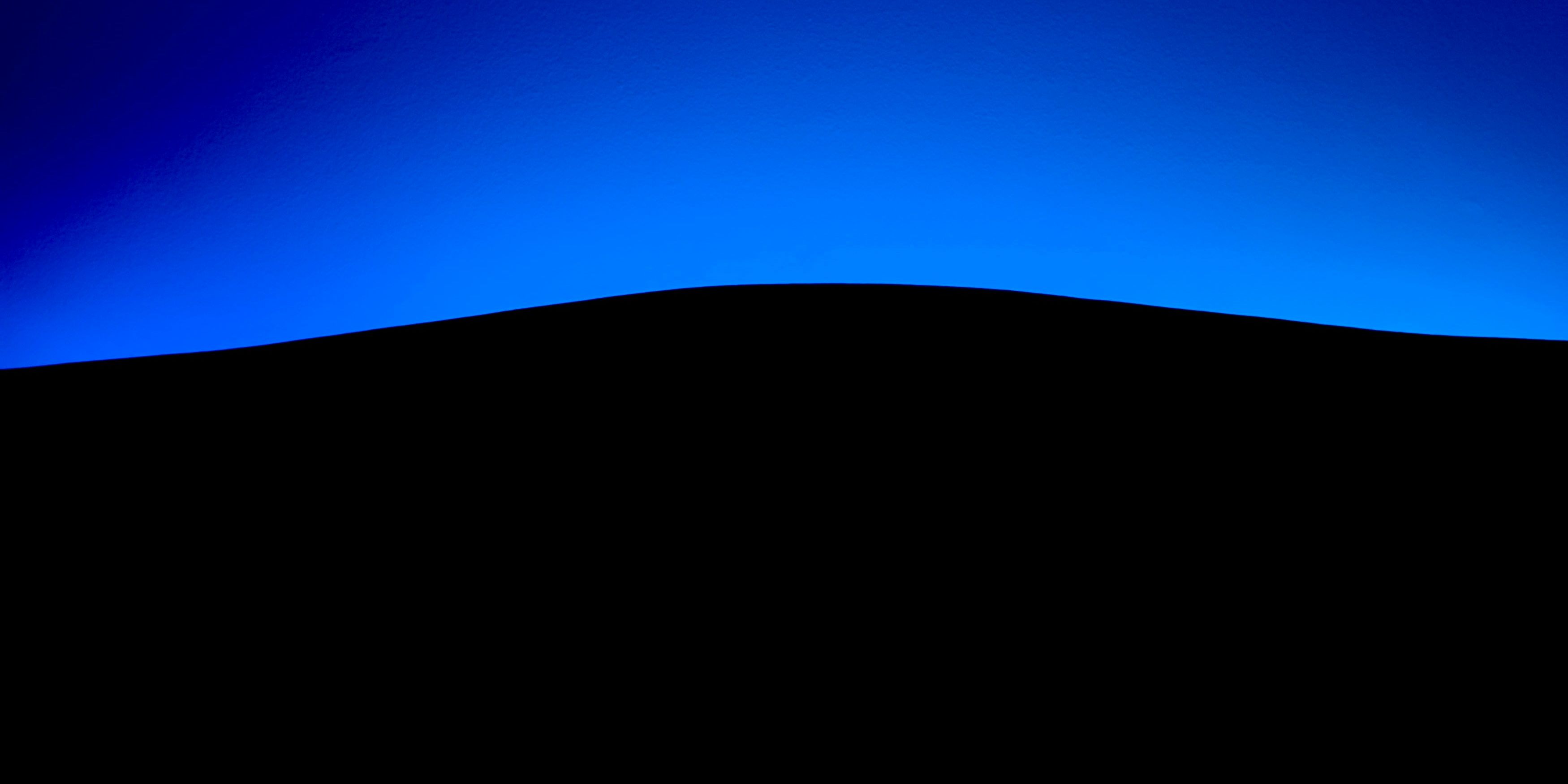 a black hill with a blue sky in the background .
