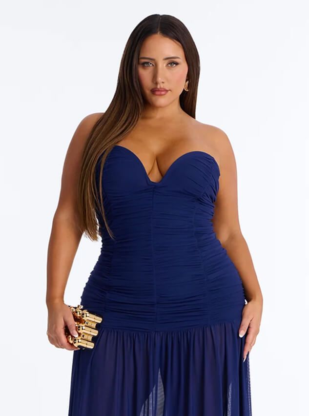 Plus size model wears a strapless blue ruched evening gown with sweetheart neckline, holding a gold clutch. Shop elegant party dresses.