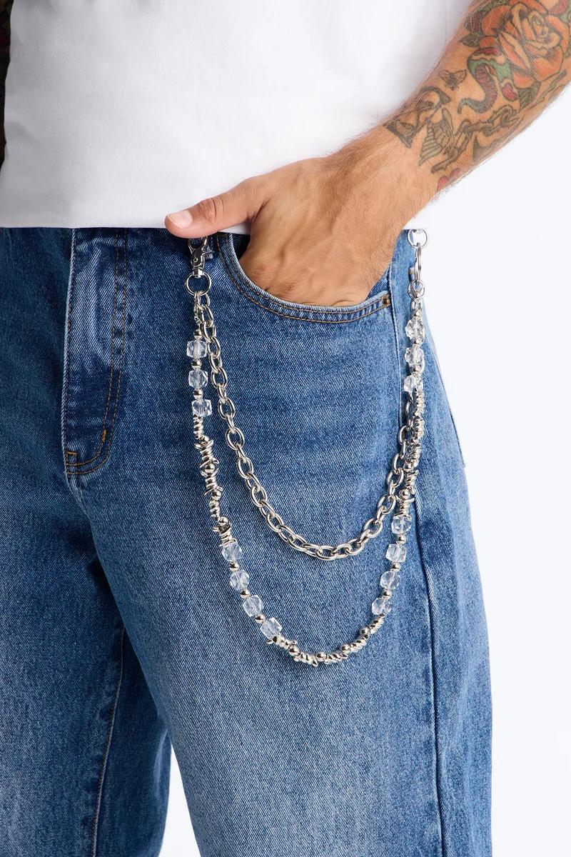 Hand in blue jeans pocket, featuring a stylish silver beaded wallet chain. Explore our new men's accessory collection.