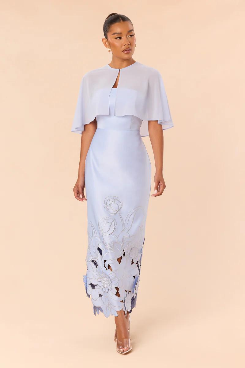Elegant light blue midi dress with sheer capelet and intricate laser-cut floral hem design, perfect for special occasions.
