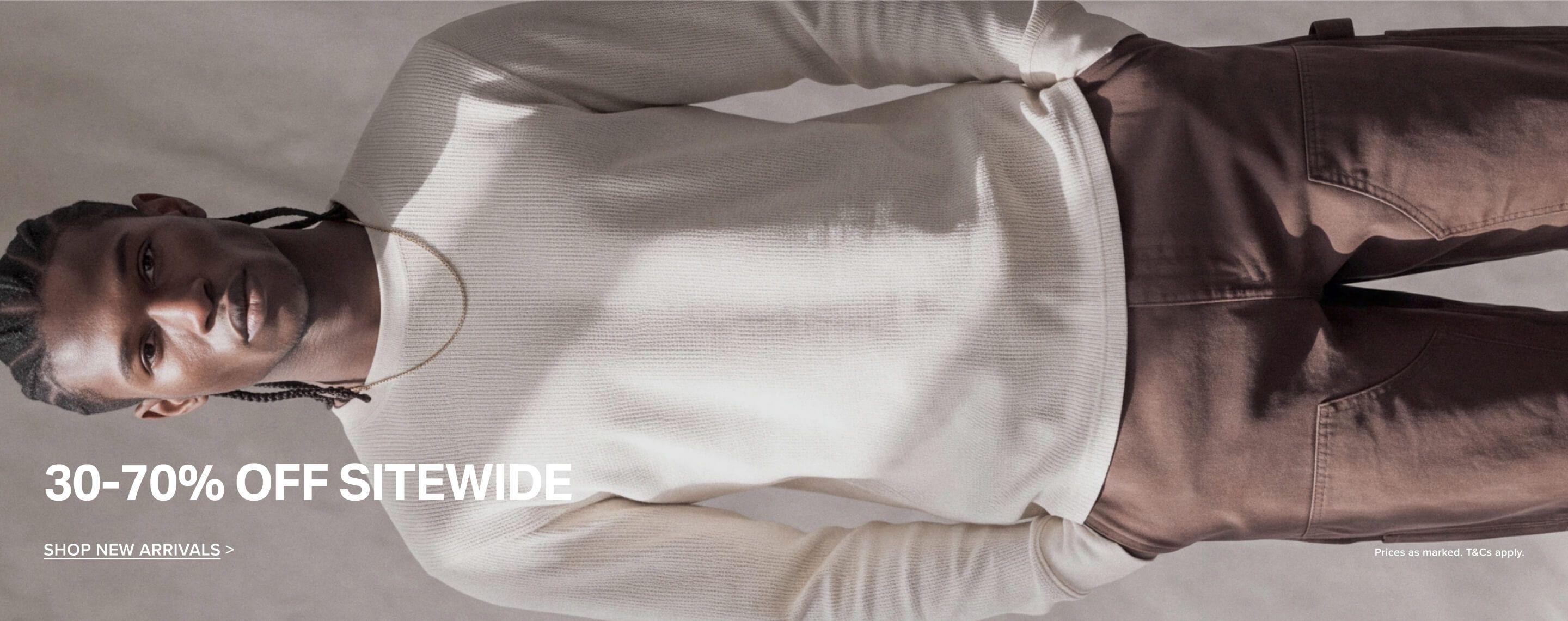 Man wearing a cream waffle-knit long-sleeve shirt and brown pants promoting a 30-70% off sitewide sale on new apparel arrivals.