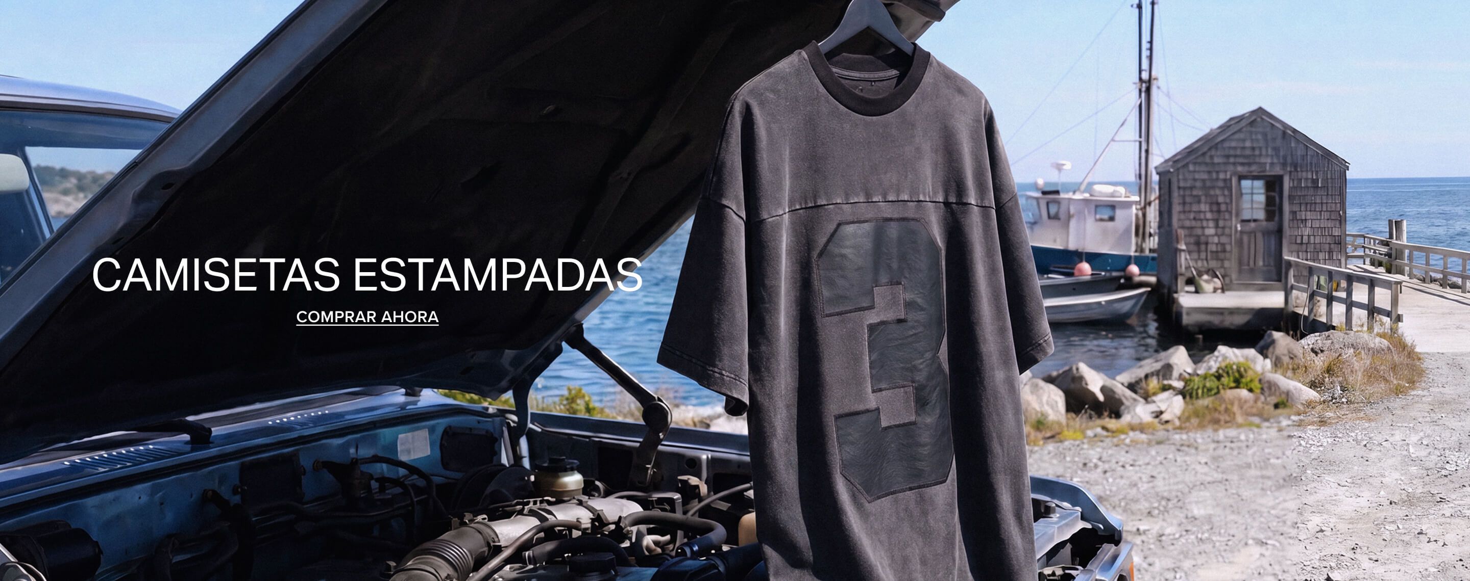 Camiseta gráfica gris desgastada con diseño audaz del número 3, colgando al aire libre junto a agua azul. ¡Descubre camisetas gráficas para hombre!
