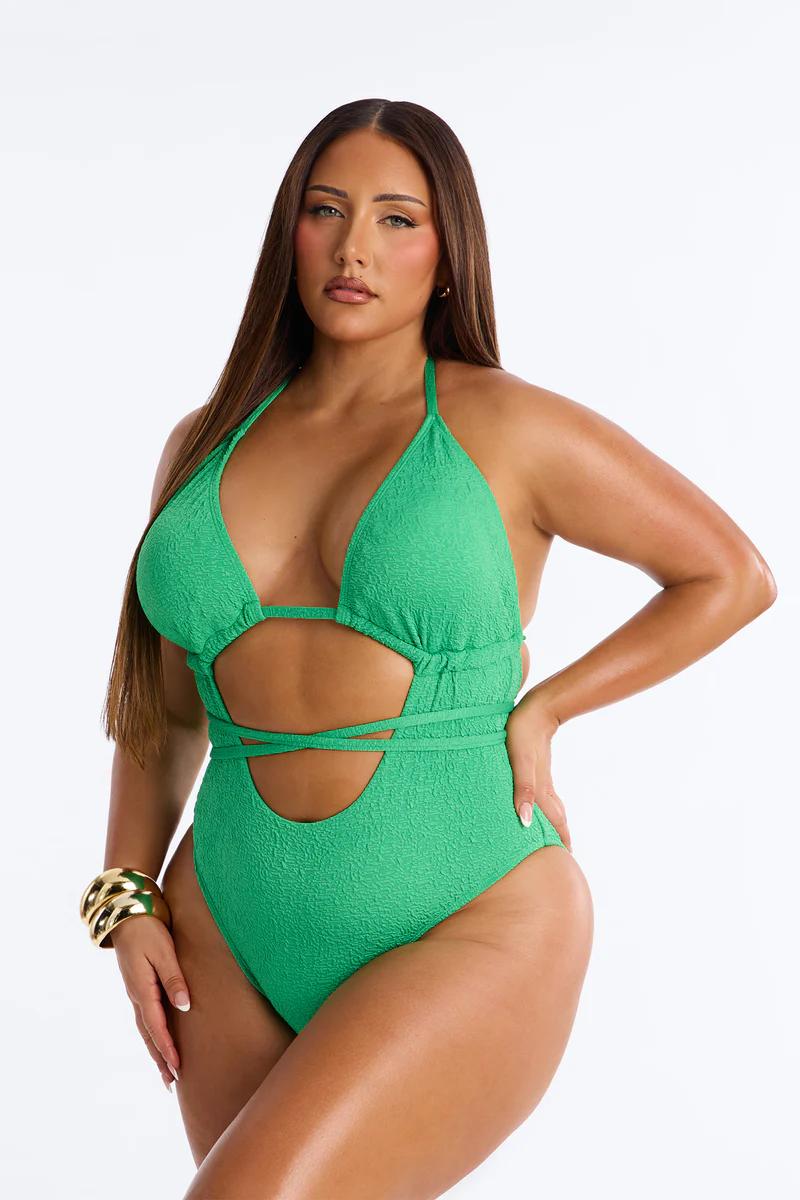 Curvy woman in emerald green textured cut-out halter neck one-piece swimsuit.