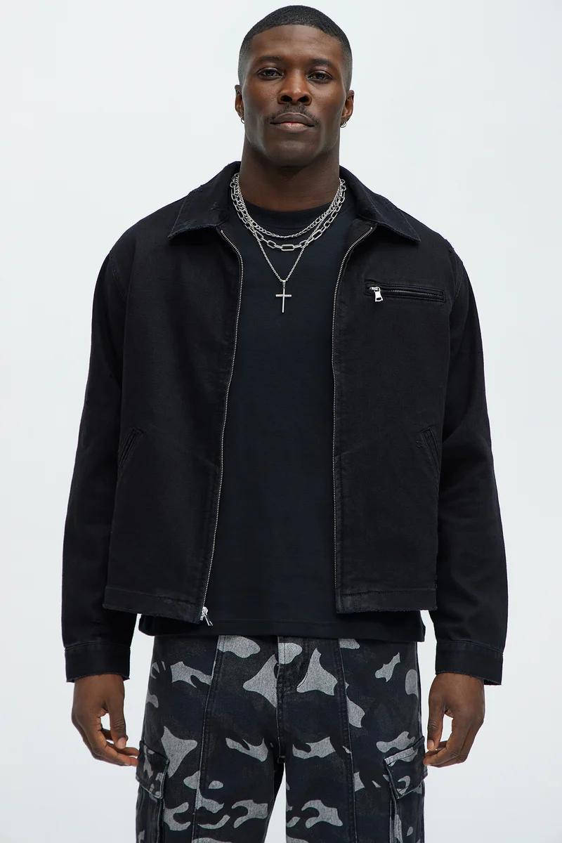 Man models black zippered jacket, black tee, and dark grey camouflage cargo pants. Discover our latest men's streetwear fashion.