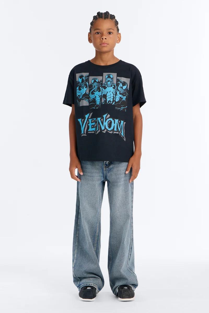 Niño con camiseta negra de Venom de Marvel y pantalones vaqueros anchos.