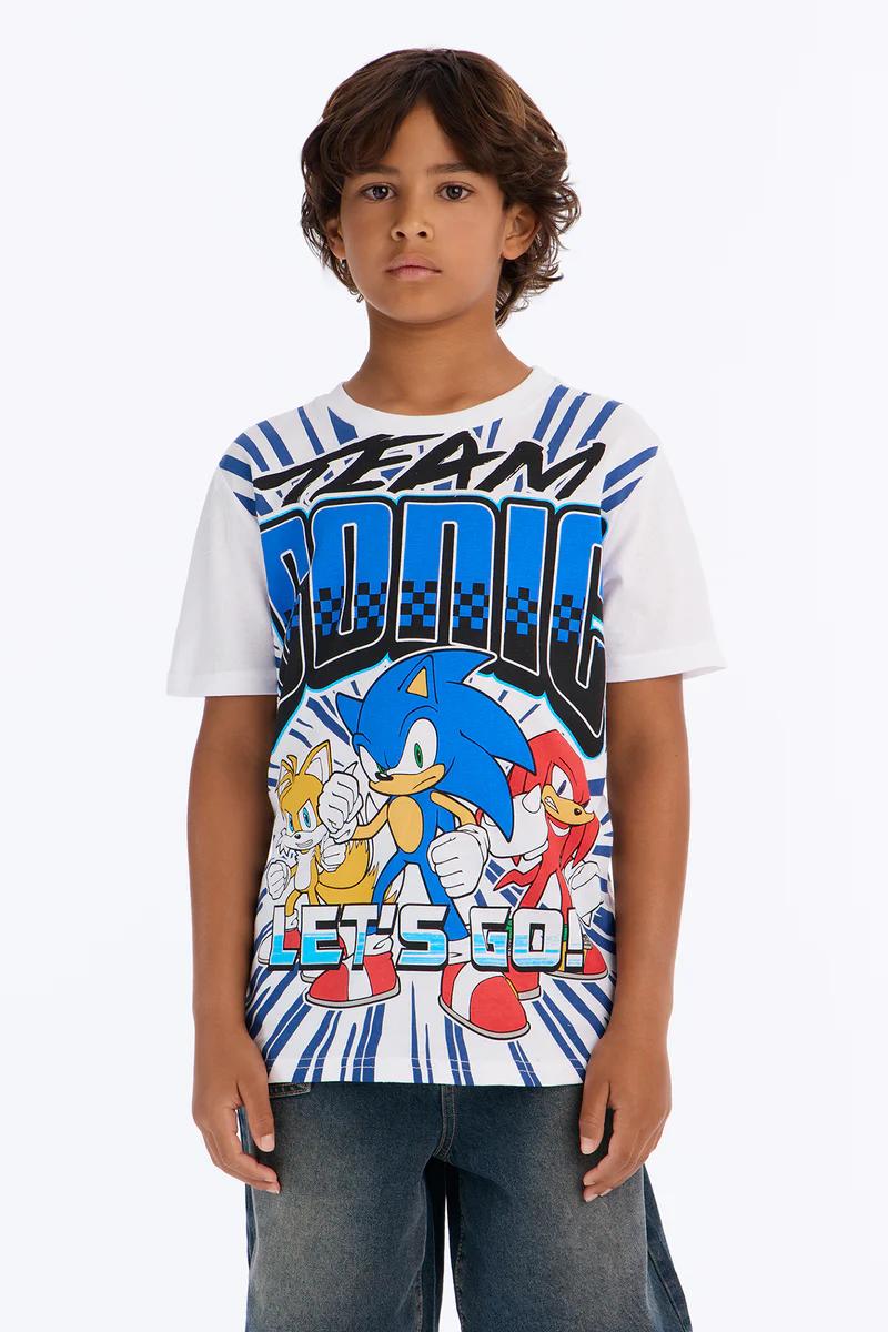 Boy in Team Sonic t-shirt with Sonic, Tails, Knuckles, denim shorts, & white high-top sneakers. Kids' apparel.