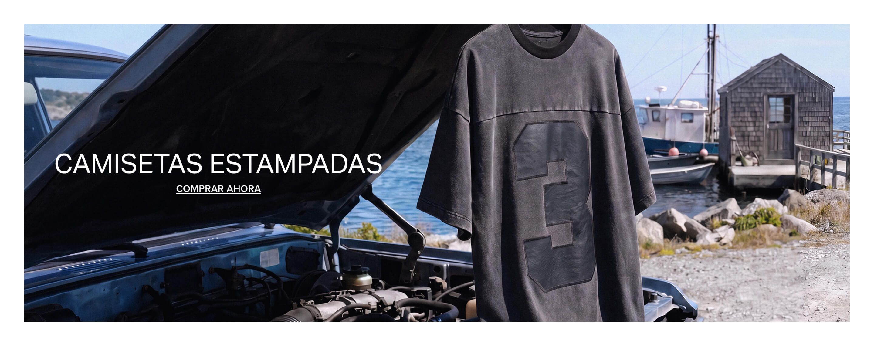 Camiseta gráfica gris desgastada con diseño audaz del número 3, colgando al aire libre junto a agua azul. ¡Descubre camisetas gráficas para hombre!