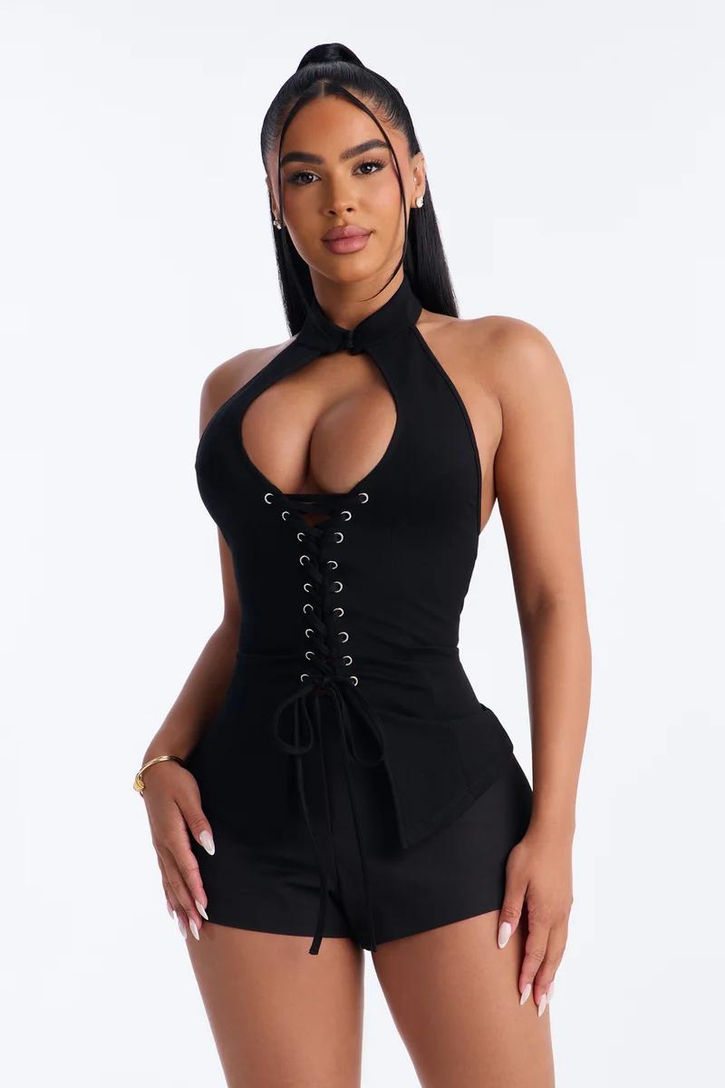 Mujer con enterizo negro de cuello halter, cordones y escote de lágrima.