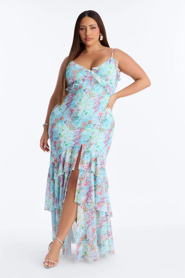 Woman modeling a plus size light blue floral print ruffled maxi dress with spaghetti straps and a high slit. Perfect summer fashion new arrival.