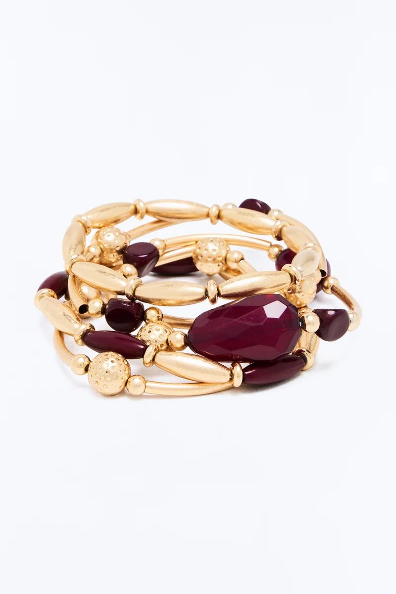 Set de pulseras elásticas de cuentas doradas y burdeos con detalles de piedras facetadas de color granate.