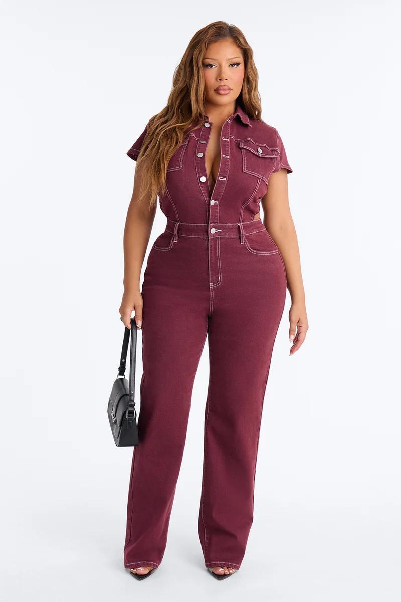 Woman in dark wash plus size denim romper with pockets, black heels, and gold jewelry, perfect for a new spring casual look.