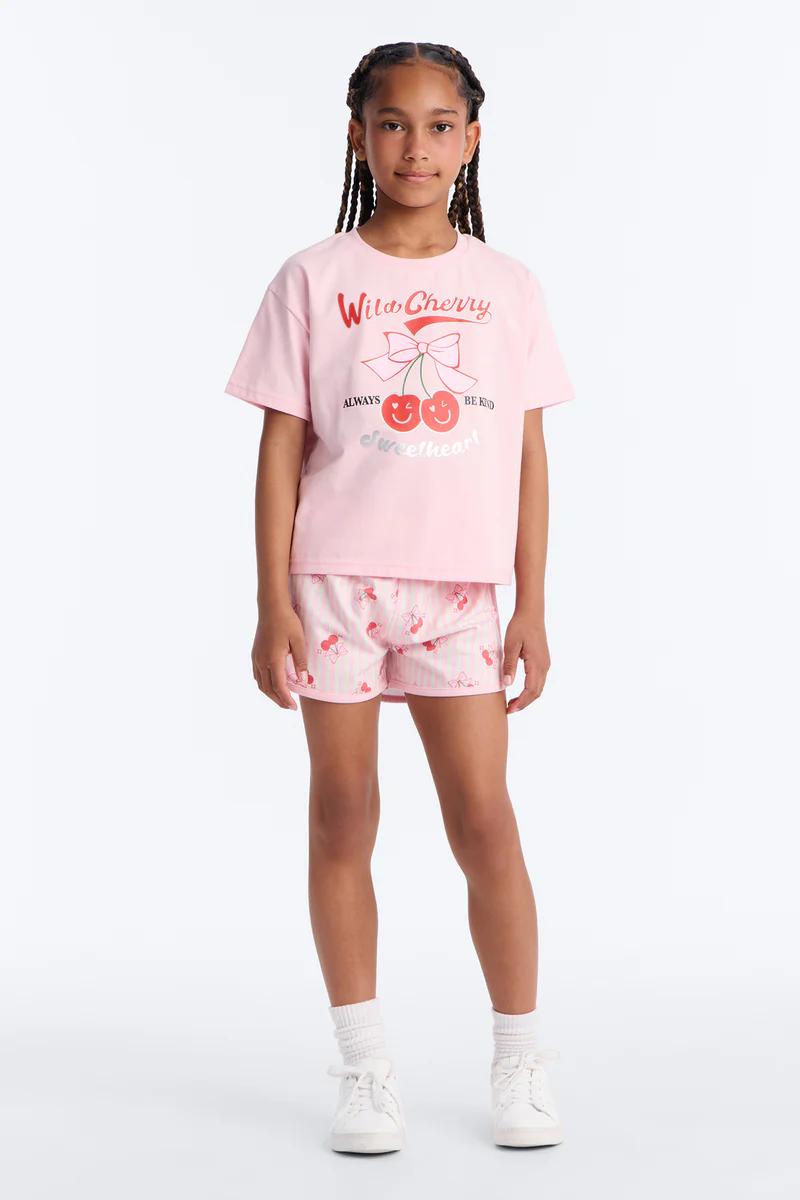 Niña con camiseta rosa Wild Cherry y shorts rosas estampado cerezas. Conjunto casual infantil.