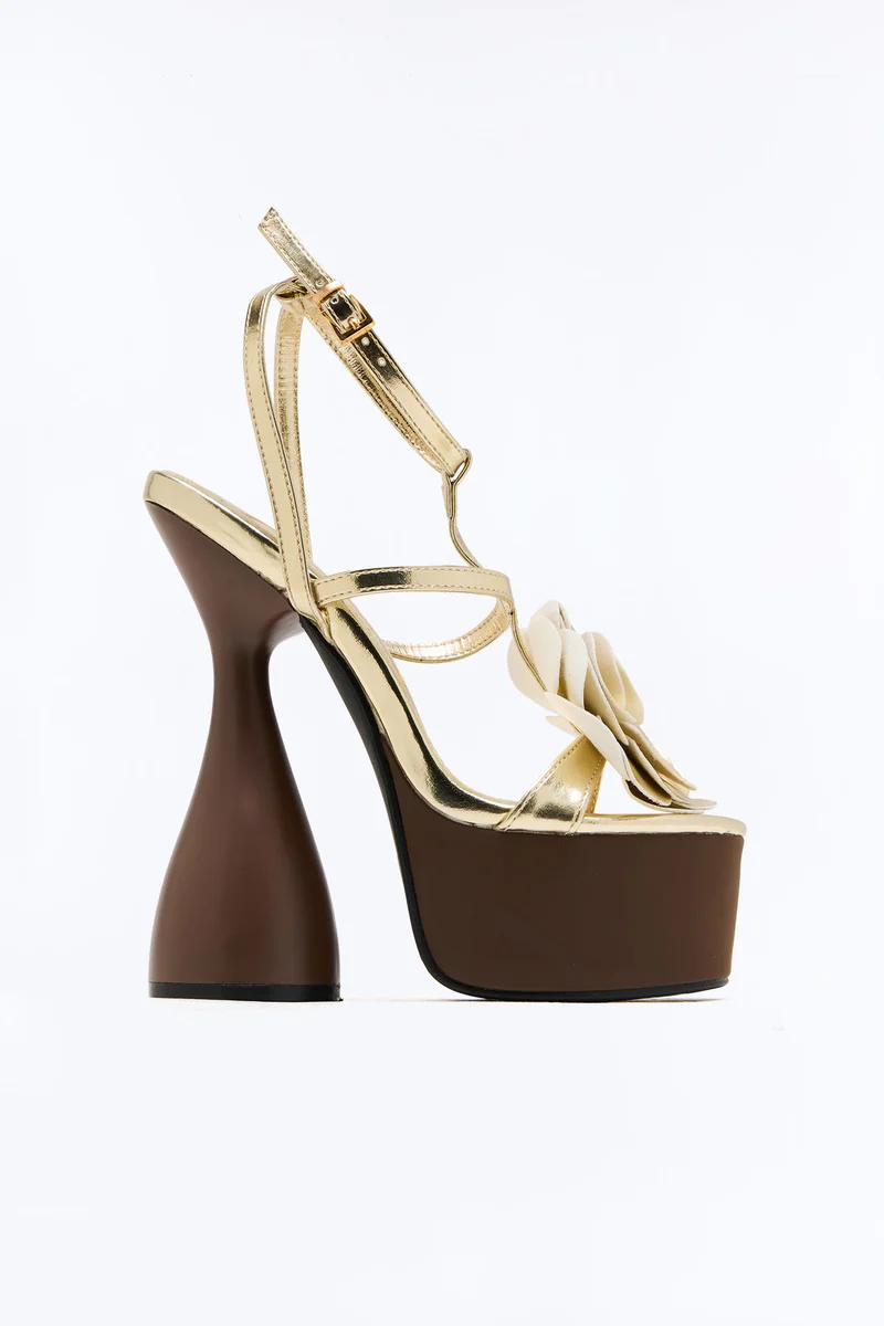 Gold platform sandal with brown flared heel, chunky brown platform, and a prominent beige floral embellishment on the strap.