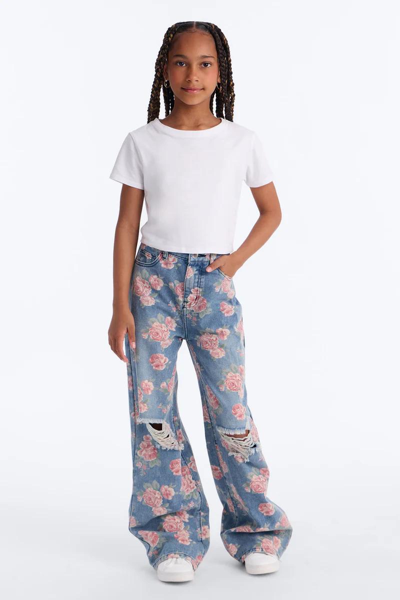 Young girl in white crop top and distressed wide-leg jeans with pink rose floral print.