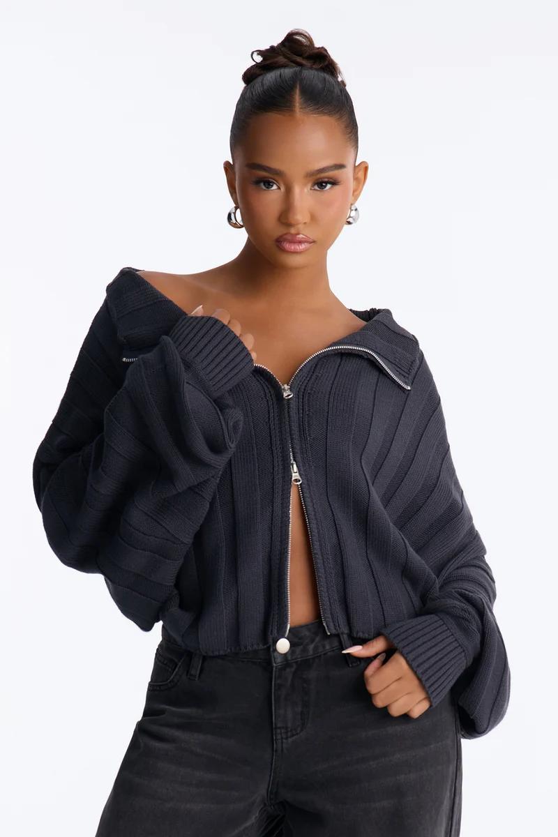 Woman in a charcoal gray ribbed zip-up knit cardigan sweater off the shoulder.