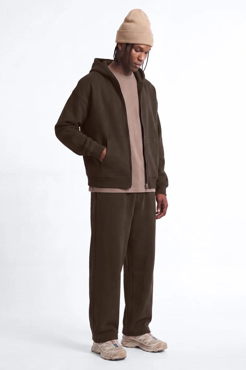 Man in dark brown full-zip hoodie, matching sweatpants, beige tee, and beanie. Comfortable men's loungewear for everyday style.